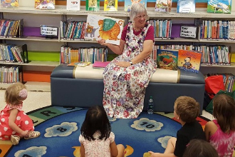 Woman reading a book to children.