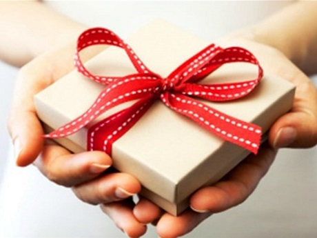 Gift box with red ribbon in a person's hands