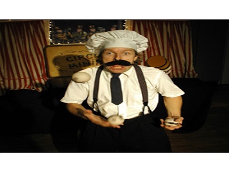 man in a chefs hat, suspenders, giant mustache juggling balls