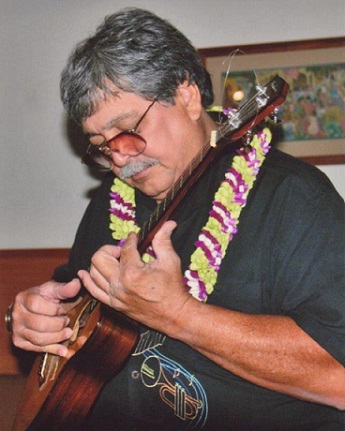 Benny Chong with lei, looking at his ukulele while playing