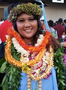 Woman wearing leis in graduation photo and smiling