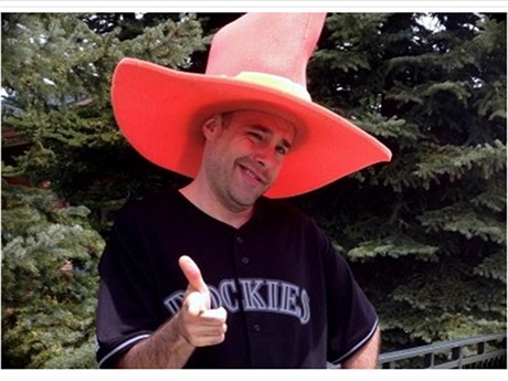 Neil McIntyre wearing a black t-shirt & large red hat