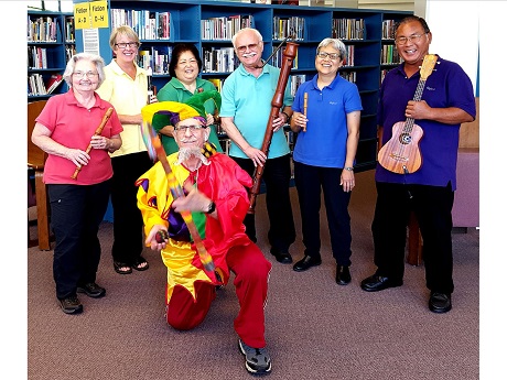 A group of musicians holding wooden recorders and a 'ukelele. A juggler is juggling in front of them.