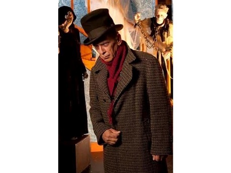 grumpy man in a top hat with spooky characters in background