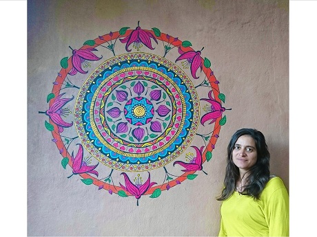 Artist Ayala Wise standing next to large mandala