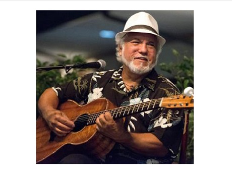 Color front-view photo of slack key guitarist John Keawe holding a guitar.