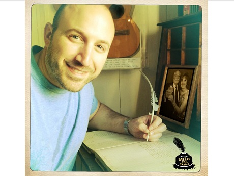 man at desk holding quill pen