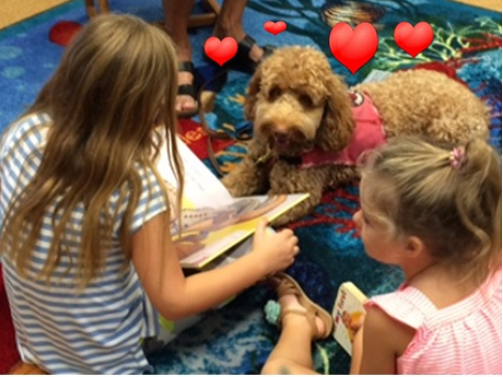 Girls reading to labradoodle