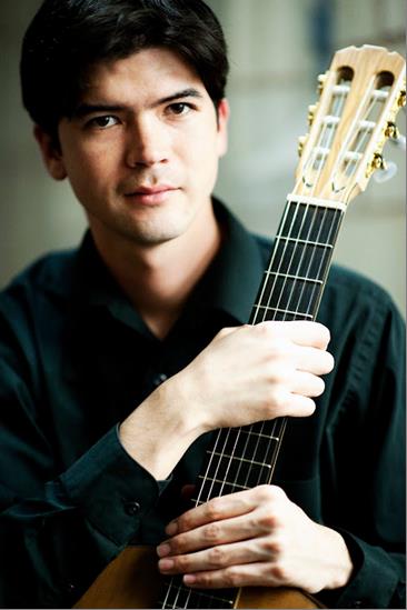 A man dressed in black holding a guitar