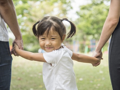 Young girl holding parents' hands