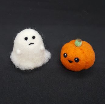 white ghost and orange pumpkin made of felt on black background