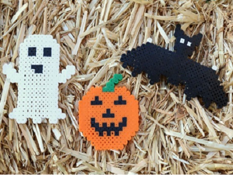 Perler bead creations in halloween shapes that include a ghost, a jack o lantern, and a bat.