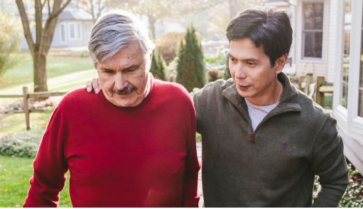 Elderly man and young man walking together