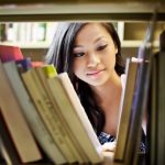 Female Teen looking at books in library