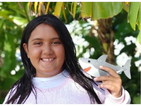 Girl smiling holding a shark sewn from felt