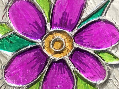 A purple flower with a yellow center and green leaves made from tin foil.