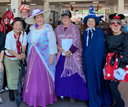 Librarians in various halloween costumes like Minnie Mouse, Mickey Mouse from Fantasia, a lady with a tiara, a sophisticated lady with a big white hat and lavish purple dress, and others