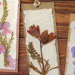 Three pressed flower bookmarks. Purple flowers are on the right, the middle has red flowers, and the left has pink.