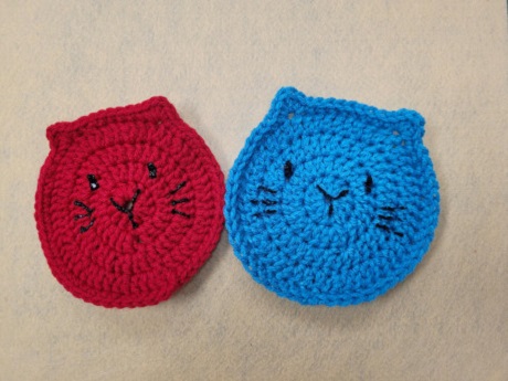2 crocheted cat coasters: red and blue.