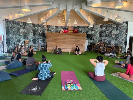 People of diverse backgrounds sitting in a circle on yoga mats in a round room.