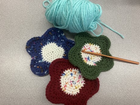 photo of three crocheted flower coasters with yarn and crochet hook